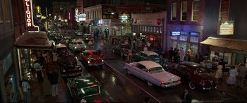 Movie still from “Elvis” (2022), directed by Baz Luhrmann – A group of cars driving down a street at night; Extreme Wide shot, High angle