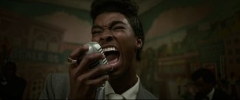 Movie still from “Elvis” (2022), directed by Baz Luhrmann – A man in a suit is singing into a microphone; Close Up shot, Overhead angle