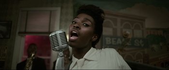 Movie still from “Elvis” (2022), directed by Baz Luhrmann – A woman singing into an old fashioned microphone; Close Up shot, Low angle
