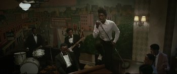 Movie still from “Elvis” (2022), directed by Baz Luhrmann – A group of men in suits singing and playing instruments; Medium shot, Low angle