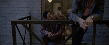 Movie still from “Elvis” (2022), directed by Baz Luhrmann – A man sitting on the ground with a cigarette in his mouth; Medium shot, Over the shoulder angle