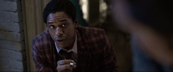 Movie still from “Elvis” (2022), directed by Baz Luhrmann – A man in a plaid jacket holding a cigarette in his hand; Close Up shot, Over the shoulder angle