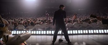 Movie still from “Elvis” (2022), directed by Baz Luhrmann – A man standing on a stage in front of an audience; Wide shot, Low angle