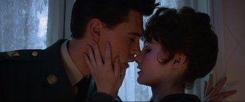 Movie still from “Elvis” (2022), directed by Baz Luhrmann – A man and a woman kissing in front of a window; Close Up shot, Low angle