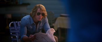 Movie still from “Elvis” (2022), directed by Baz Luhrmann – A man sitting down reading a newspaper; Medium shot, Over the shoulder angle