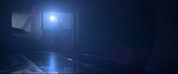 Movie still from “Elvis” (2022), directed by Baz Luhrmann – A man standing in a dark room with a light shining on him; Wide shot, Low angle