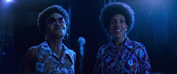 Movie still from “Elvis” (2022), directed by Baz Luhrmann – Two women standing next to each other in front of a microphone; Medium shot, Low angle