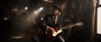 Movie still from “Elvis” (2022), directed by Baz Luhrmann – A man in a suit and hat playing an acoustic guitar; Medium shot, Low angle