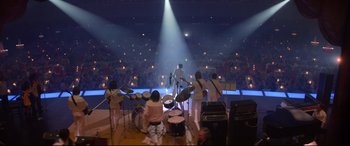 Movie still from “Elvis” (2022), directed by Baz Luhrmann – A group of people playing musical instruments on a stage; Extreme Wide shot, High angle