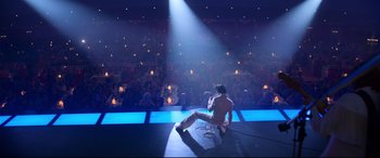 Movie still from “Elvis” (2022), directed by Baz Luhrmann – A man sitting on the ground in front of an audience; Extreme Wide shot, High angle
