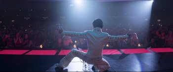 Movie still from “Elvis” (2022), directed by Baz Luhrmann – A man in a white jacket is on a stage; Wide shot, Low angle