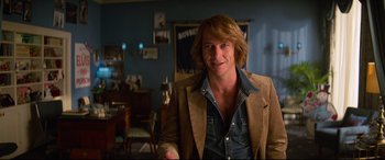 Movie still from “Elvis” (2022), directed by Baz Luhrmann – A man with long blonde hair wearing a brown jacket; Medium shot, Over the shoulder angle