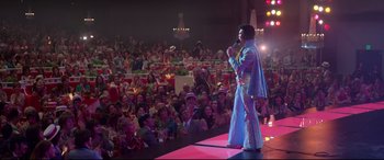 Movie still from “Elvis” (2022), directed by Baz Luhrmann – A man dressed as elvis presley on a stage with a crowd; Extreme Wide shot, Low angle