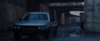 Movie still from “The Accountant” (2016), directed by Gavin O'Connor – A car parked under a bridge in the rain; Extreme Wide shot, Low angle