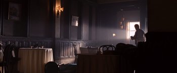 Movie still from “The Accountant” (2016), directed by Gavin O'Connor – A room with a table and chairs and a cross on the wall; Wide shot, Low angle