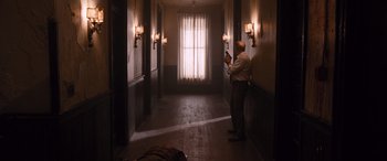 Movie still from “The Accountant” (2016), directed by Gavin O'Connor – A man taking a picture in a dark hallway; Wide shot, High angle