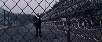 Movie still from “The Accountant” (2016), directed by Gavin O'Connor – A man standing in front of a chain link fence; Wide shot, Low angle