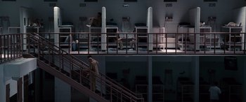 Movie still from “The Accountant” (2016), directed by Gavin O'Connor – A man walking up a flight of stairs in a building; Extreme Wide shot, High angle