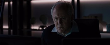 Movie still from “The Accountant” (2016), directed by Gavin O'Connor – An older man is sitting in front of a computer screen; Close Up shot, Over the shoulder angle