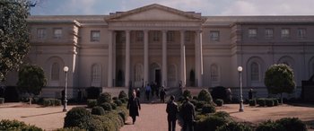 Movie still from “The Accountant” (2016), directed by Gavin O'Connor – A group of people walking in front of a large building; Extreme Wide shot, Low angle