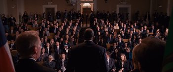 Movie still from “The Accountant” (2016), directed by Gavin O'Connor – A crowd of people sitting in front of a man in a suit; Extreme Wide shot, High angle