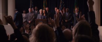 Movie still from “The Accountant” (2016), directed by Gavin O'Connor – A group of people standing in front of a podium; Medium shot, Low angle