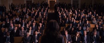 Movie still from “The Accountant” (2016), directed by Gavin O'Connor – A group of people sitting in front of an audience; Wide shot, High angle