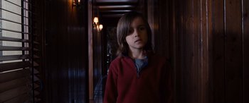 Movie still from “The Accountant” (2016), directed by Gavin O'Connor – A young boy in a red jacket standing in a dark hallway; Medium shot, Over the shoulder angle