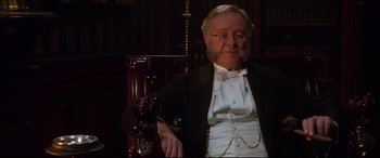 Movie still from “The Age of Innocence” (1993), directed by Martin Scorsese – An old man in a suit sitting in a chair; Close Up shot, Low angle