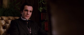 Movie still from “The Age of Innocence” (1993), directed by Martin Scorsese – A man in a suit and tie in front of a book shelf; Close Up shot, Low angle