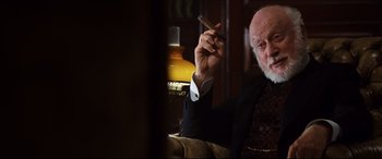 Movie still from “The Age of Innocence” (1993), directed by Martin Scorsese – An older man holding a cigar and looking at the camera; Medium shot, Over the shoulder angle