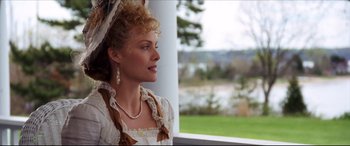 Movie still from “The Age of Innocence” (1993), directed by Martin Scorsese – A woman wearing a white dress and pearls looking out of a window; Close Up shot, Low angle