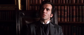 Movie still from “The Age of Innocence” (1993), directed by Martin Scorsese – A man wearing a suit and tie sitting in a chair; Close Up shot, Low angle