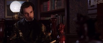 Movie still from “The Age of Innocence” (1993), directed by Martin Scorsese – A man sitting in a chair in a library; Medium shot, Over the shoulder angle