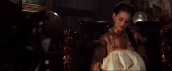 Movie still from “The Age of Innocence” (1993), directed by Martin Scorsese – A woman sitting on top of a couch in front of a vase; Medium shot, Over the shoulder angle
