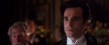 Movie still from “The Age of Innocence” (1993), directed by Martin Scorsese – A person wearing a suit and tie; Close Up shot, Over the shoulder angle