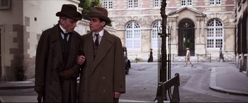 Movie still from “The Age of Innocence” (1993), directed by Martin Scorsese – A couple of men standing next to each other on a street; Medium shot, Over the shoulder angle
