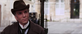 Movie still from “The Age of Innocence” (1993), directed by Martin Scorsese – A man wearing a hat and a brown coat; Close Up shot, Over the shoulder angle