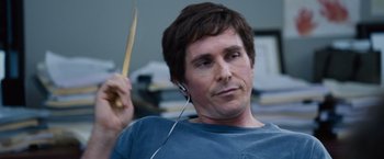 Movie still from “The Big Short” (2015), directed by Adam McKay – A man holding a wooden stick while listening to music; Close Up shot, Over the shoulder angle