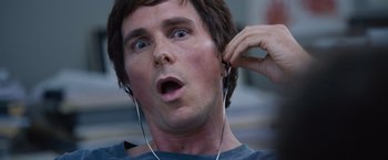 Movie still from “The Big Short” (2015), directed by Adam McKay – A person wearing headphones and looking surprised; Close Up shot, Low angle