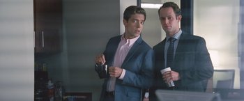 Movie still from “The Big Short” (2015), directed by Adam McKay – A man in a suit and tie next to another man in a suit and tie; Medium shot, Over the shoulder angle