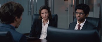 Movie still from “The Big Short” (2015), directed by Adam McKay – A woman sitting at a table in a conference room; Medium shot, Over the shoulder angle