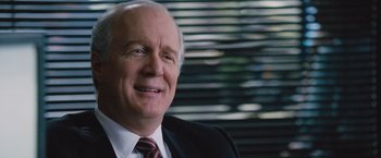 Movie still from “The Big Short” (2015), directed by Adam McKay – An older man wearing a suit and tie; Close Up shot, Over the shoulder angle