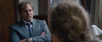 Movie still from “The Big Short” (2015), directed by Adam McKay – A man wearing a suit and tie sitting in front of another man in a suit; Close Up shot, Over the shoulder angle