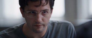Movie still from “The Big Short” (2015), directed by Adam McKay – A person wearing glasses and looking at the camera; Close Up shot, Over the shoulder angle