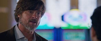 Movie still from “The Big Short” (2015), directed by Adam McKay – A person wearing glasses with a cross in the background; Close Up shot, Over the shoulder angle