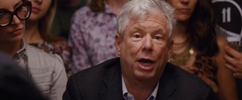 Movie still from “The Big Short” (2015), directed by Adam McKay – An older man in a black suit and white hair; Close Up shot, Over the shoulder angle