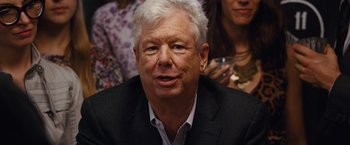 Movie still from “The Big Short” (2015), directed by Adam McKay – An older man in a black suit and white hair; Close Up shot, Over the shoulder angle
