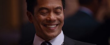 Movie still from “The Big Short” (2015), directed by Adam McKay – A person wearing a suit and tie smiling; Close Up shot, Over the shoulder angle