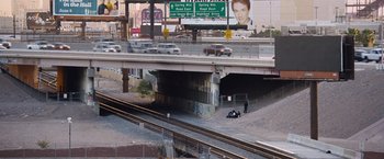 Movie still from “The Big Short” (2015), directed by Adam McKay – A person is sitting on a motorcycle on the side of the road; Extreme Wide shot, High angle